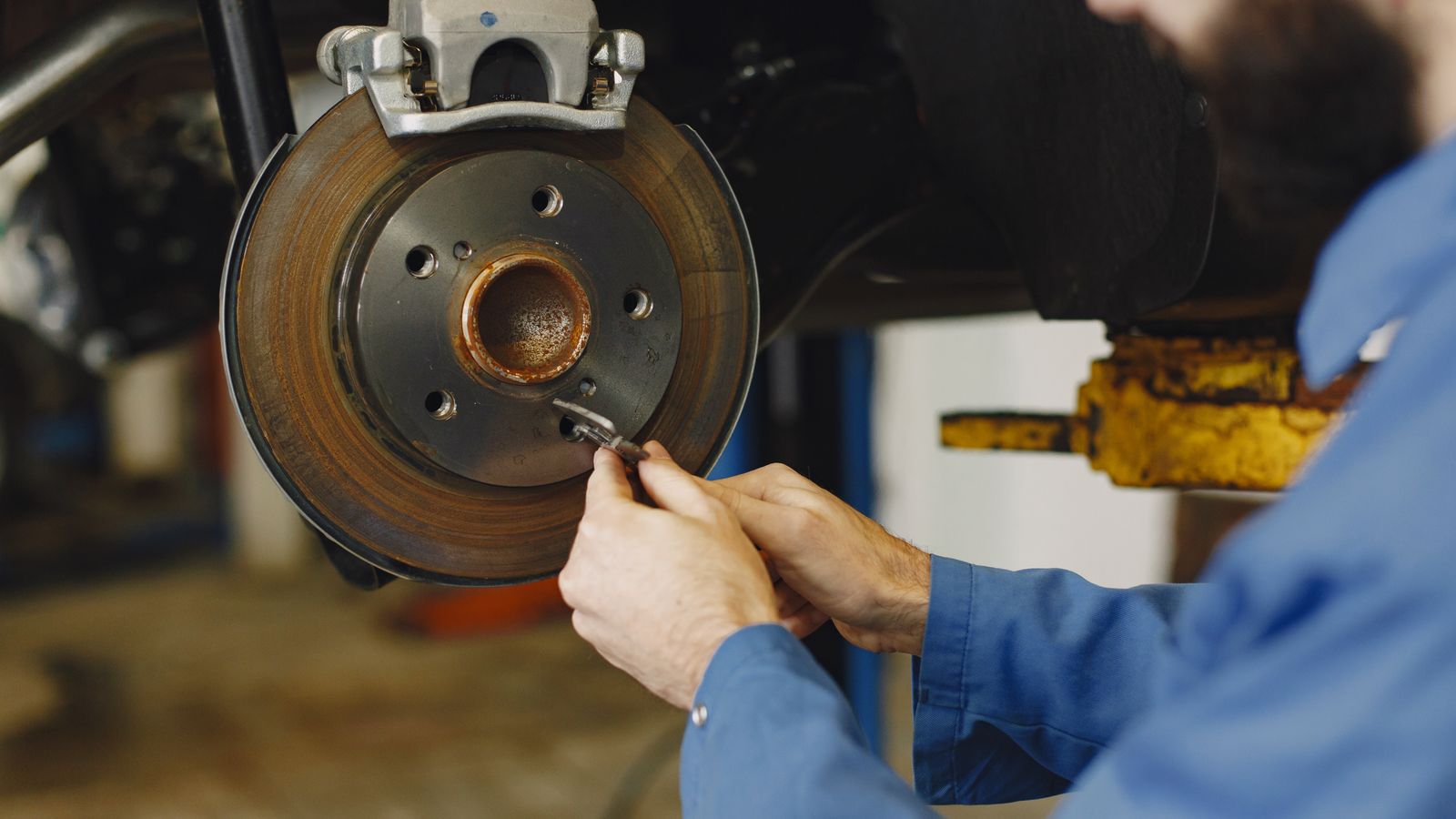 Mechanic working on brake disc in an auto repair workshop, close-up, focus on hands.
