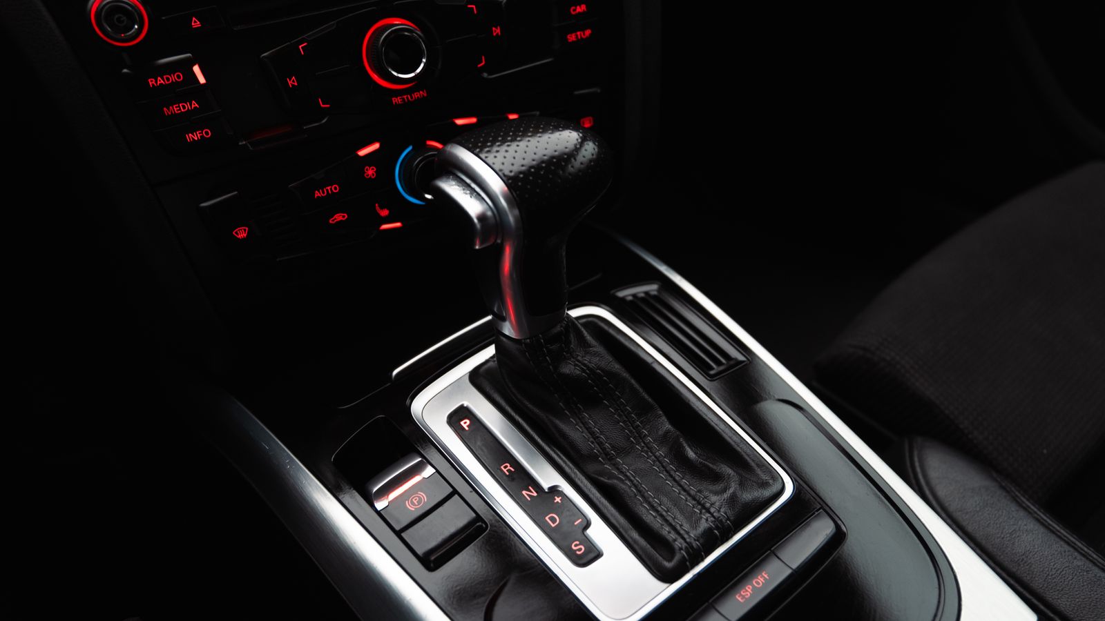 Close-up shot of a modern car gear shift lever and control panel, highlighting details.