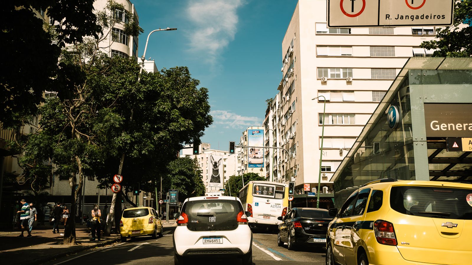 Capture of a lively street in Rio de Janeiro, featuring traffic and pedestrians on a sunny day.