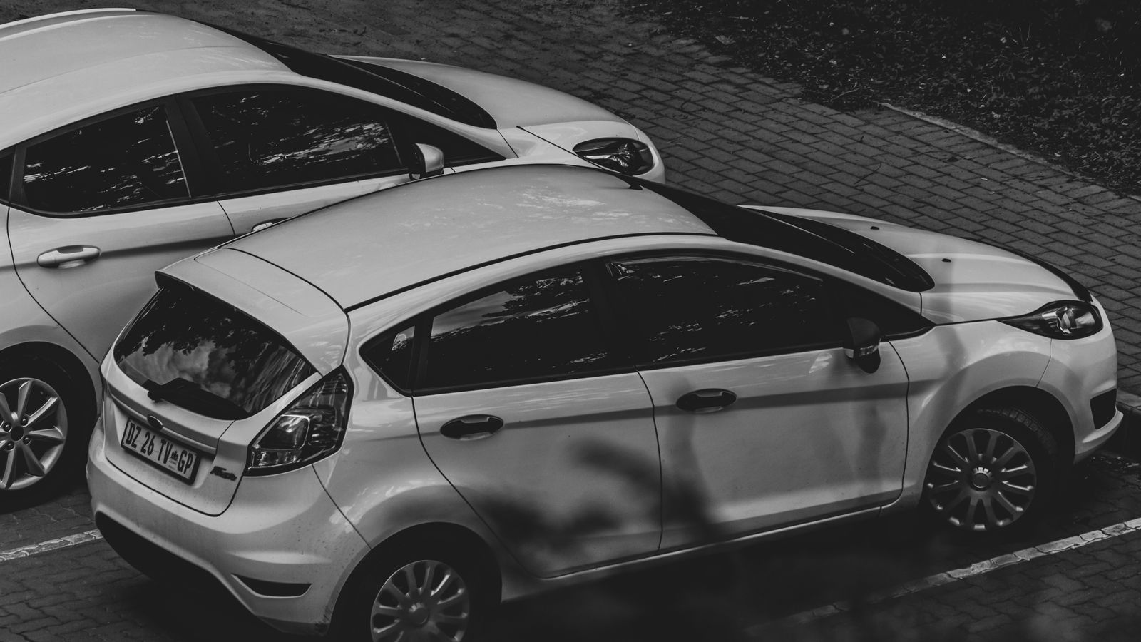 A monochrome image showcasing parked cars in an urban environment.