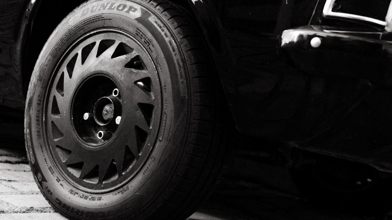 Detailed monochrome shot of a black sports car wheel displaying intricate design.